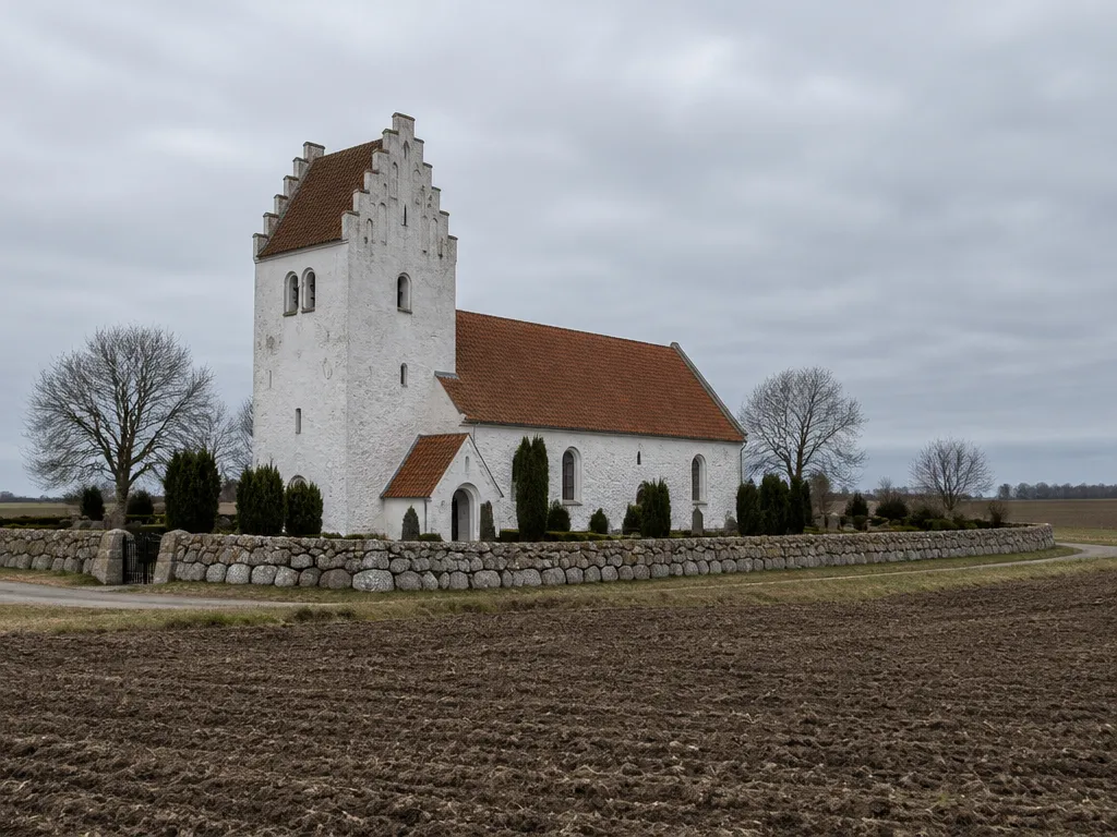 Gammal stenkyrka och kyrkogårdsmur i skånskt slättlandskap en grå dag
